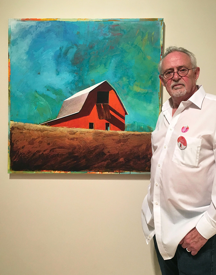 Roger Harvey next to one of his landscape paintings